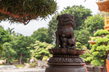 A Chinese lion statue with Chinese garden background,