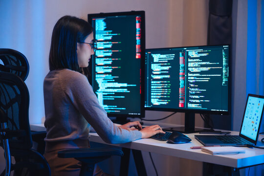 Asian woman  software development working on coding  computer screen and flowchart at night in modern office