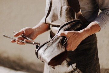 Shoemaker working on a leather shoe with tools in hand
