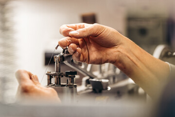 Hands working on a sewing machine in a detailed close-up
