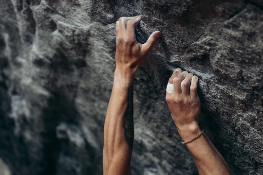 Close-up of climber's hands on rugged rock surface