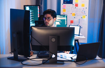 Asian software developers working on multiple screens displaying code and application diagrams at...