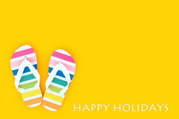 Rainbow flip flops for happy holidays concept. Casual summer footwear on yellow background. Beach...