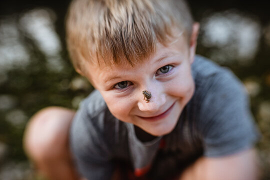 Close up of child smiling with tiny frog on his face