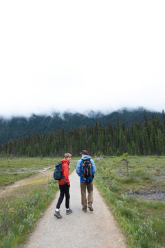 A man and boy walk along a dirt path on a cool, cloudy day.