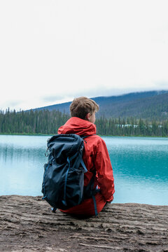 A tween boy wearing a backpack sits on a rock overlooking Emeral