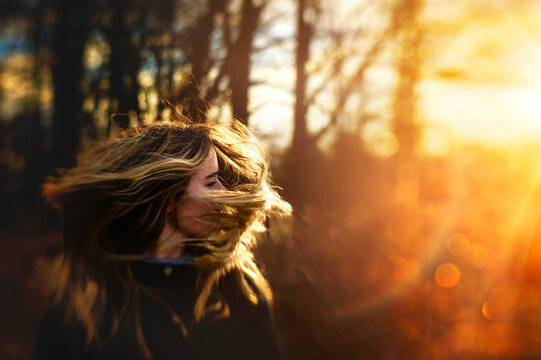 Beautiful teen girl flipping hair in golden sunlight