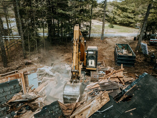 Heavy machinery excavator uses bucket to demolish old home, Maine