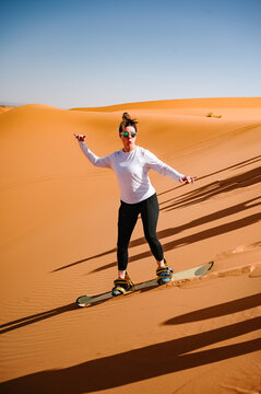 A woman tries sand boarding in the Sahara Desert.