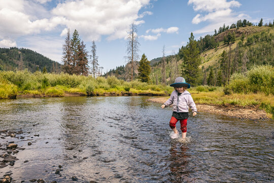 Child playing in a crystal clear stream in a forested area