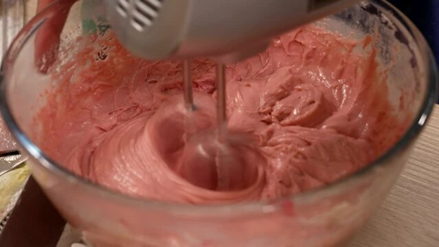 the pastry chef mixes the pink cream for the birthday cake
