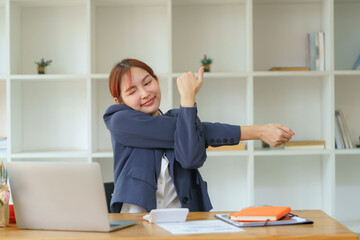 Asian businesswomen feel tired from hard work, thus doing arm stretching to relax the body. Tired...