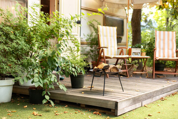 Metal black fireplace bowl with logs in garden. Backyard with RV house with garden furniture and...
