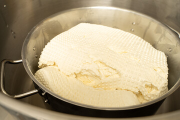 The process of making Italian mozzarella, ricotta. The workpiece is settled in a metal pan.