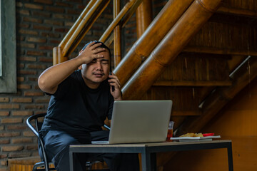 Young Asian man, digital nomad working remotely from cafe, using laptop and smartphone. young Asian...