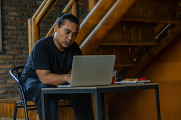 Young Asian man, digital nomad working remotely from cafe, using laptop and smartphone. young Asian...