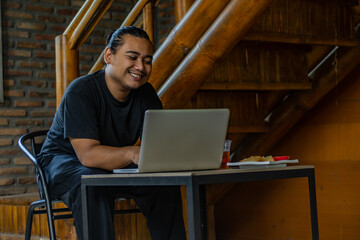 Young Asian man, digital nomad working remotely from cafe, using laptop and smartphone. young Asian...