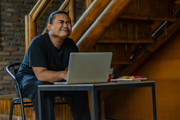 Young Asian man, digital nomad working remotely from cafe, using laptop and smartphone. young Asian...
