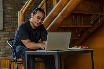 Young Asian man, digital nomad working remotely from cafe, using laptop and smartphone. young Asian...