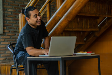 Young Asian man, digital nomad working remotely from cafe, using laptop and smartphone. young Asian...