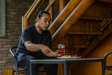 Young Asian man, digital nomad working remotely from cafe, using laptop and smartphone. young Asian...