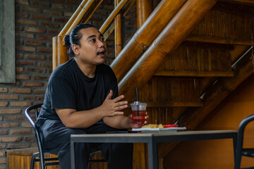 Young Asian man, digital nomad working remotely from cafe, using laptop and smartphone. young Asian...