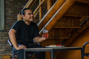 Young Asian man, digital nomad working remotely from cafe, using laptop and smartphone. young Asian...