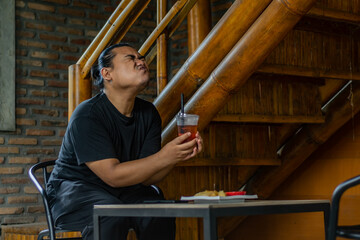 Young Asian man, digital nomad working remotely from cafe, using laptop and smartphone. young Asian men are hanging out in a cafe with an industrial theme