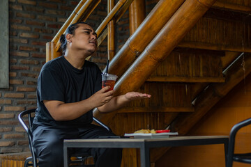 Young Asian man, digital nomad working remotely from cafe, using laptop and smartphone. young Asian...