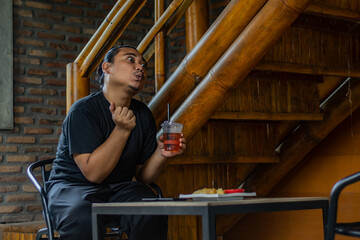 Young Asian man, digital nomad working remotely from cafe, using laptop and smartphone. young Asian...