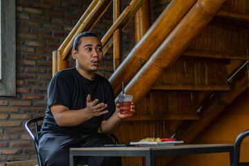 Young Asian man, digital nomad working remotely from cafe, using laptop and smartphone. young Asian...