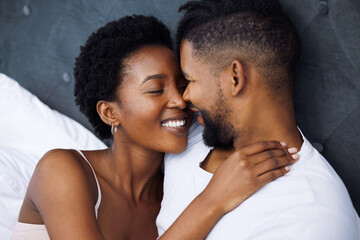 Obraz premium Black couple and embrace in bed with smile for love, together and care on weekend morning. Comfort, dating and relaxing with passion for partner with relationship, waking up and rest in house.