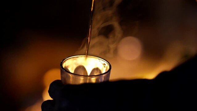 on a summer night, a typical Moroccan tea poured in front of the fire
