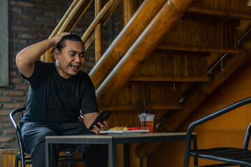 Young asian men, digital nomad working remotely from a cafe, using  smartphone.