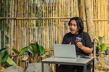 Young asian men, digital nomad working remotely from a cafe, drinking coffee and using laptop.