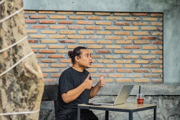Young asian men, digital nomad working remotely from a cafe, drinking coffee and using laptop.