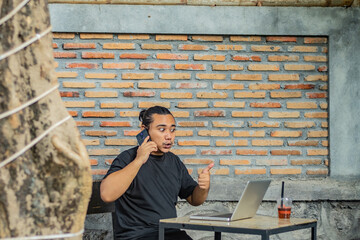 Young asian men, digital nomad working remotely from a cafe, drinking coffee and using laptop.