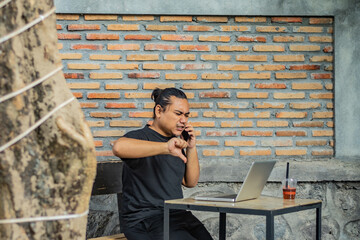 Young asian men, digital nomad working remotely from a cafe, drinking coffee and using laptop.