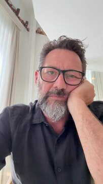 Camera view of bored adult man scrolling content pages online on mobile phone cellular app smartphone with tired expression boring watching social media. Web camera view of user scrolling internet