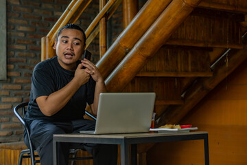 Young asian men, digital nomad working remotely from a cafe, using  smartphone.
