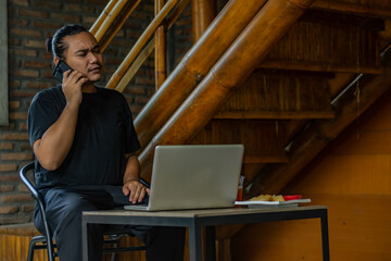 Young asian men, digital nomad working remotely from a cafe, using  smartphone.
