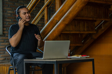Young asian men, digital nomad working remotely from a cafe, using  smartphone.