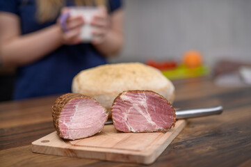 Domowa szynka, schab i baleron leżą obok chleba na kuchennym blacie