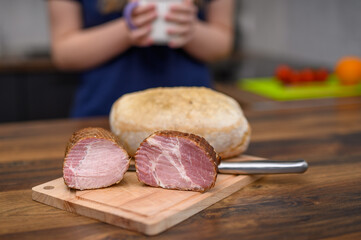 Domowa wędlina przekrojona na pół leży na desce do krojenia, polędwica i baleron 