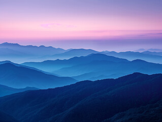 Serene view of misty blue mountain ranges under a colorful pink and purple sunrise sky, showcasing natural beauty and calmness.