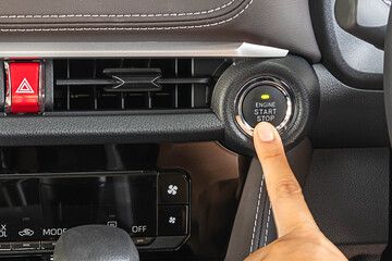 Woman uses her finger pressing the Engine start stop button of a car