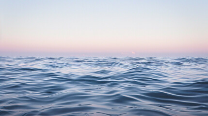 Obraz premium The calm ocean, bathed in the soft light of dawn, with gentle waves shimmering in hues of pale lavender and powder blue, blending seamlessly into the tranquil horizon.