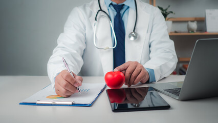 Doctor showing a red heart at hospital office, Healthcare worker and doctor service, Digital laptop in modern office, Medical technology concept, Health insurance concept, Health planning concept.