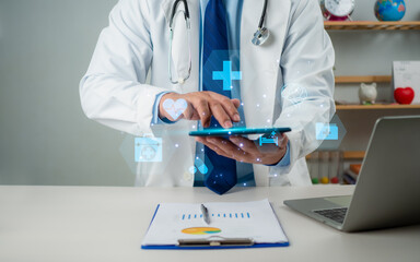 Male doctor using tablet to review treatment plan and write document reports in hospital office, Healthcare worker and doctor service, Digital laptop in modern office, Medical technology concept.