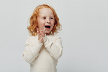 Happy little girl clapping hands in joyful expression against white background for kids...